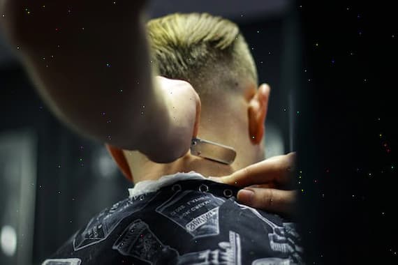 Barber shaving customer's neck with razor in salon